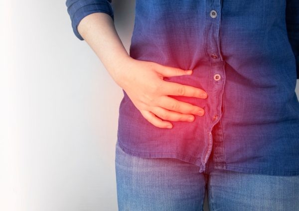 Woman clutches at her midsection, experiencing discomfort from Crohn's Disease.