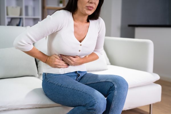 Middle class woman feels pain in her midsection due to recurrent diverticulitis.
