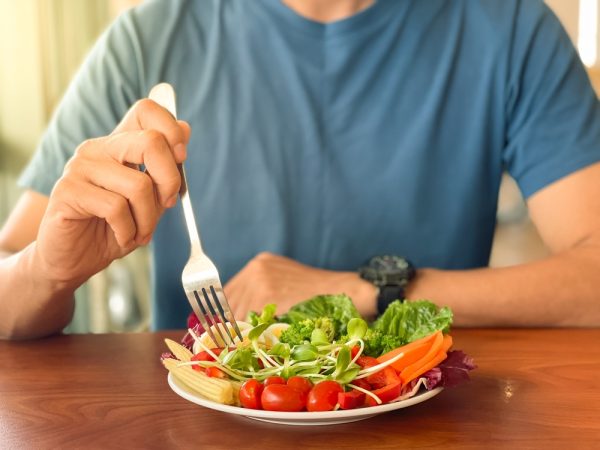Man eating a salad, minding his nutrition to better control his ulcerative colitis.