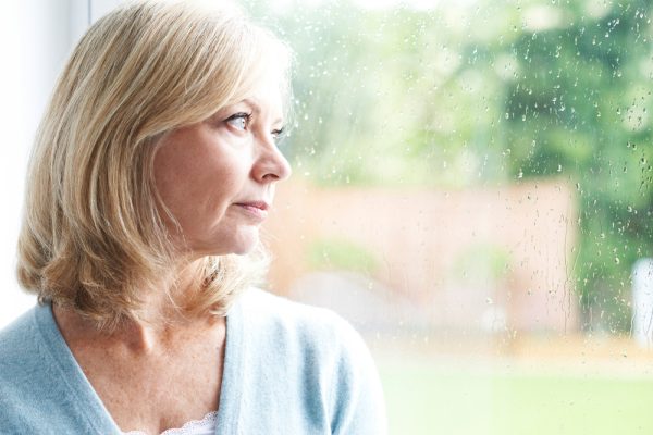 Woman looks out the window, worried that her colon polyps could turn to cancer.