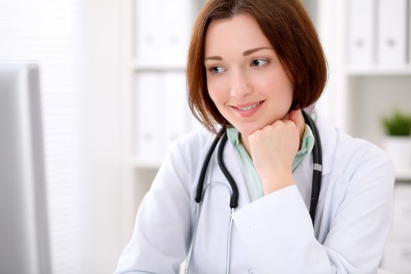 Young doctor sitting at her computer planning colon surgery.